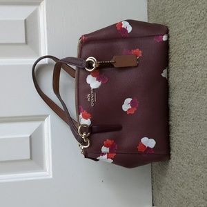 Small burgundy Coach purse with pink, orange, and white flowers.